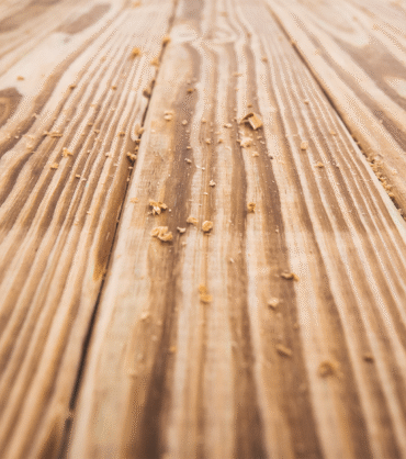 the photo shows a wooden board with visible grain and wood particles