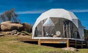 White glamping tent on a wooden deck.