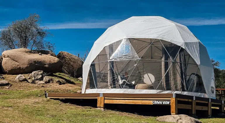 White glamping tent on a wooden deck.