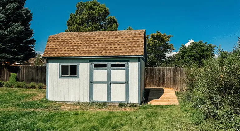 A wooden cottage on a plot with a wooden deck.