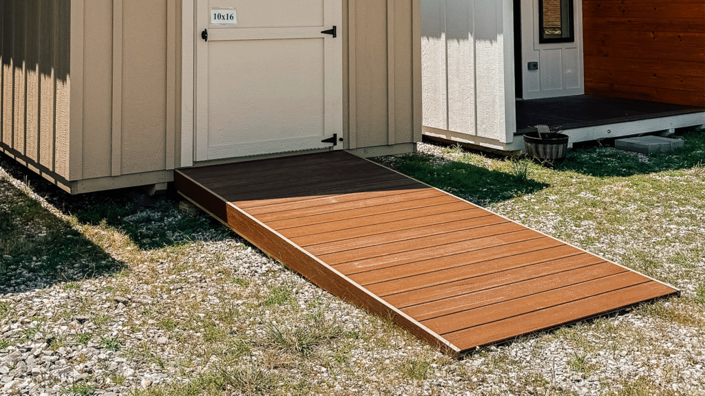 A small shed with a beige exterior featuring a brown composite deck ramp made of Trex boards, providing easy access to the entrance.