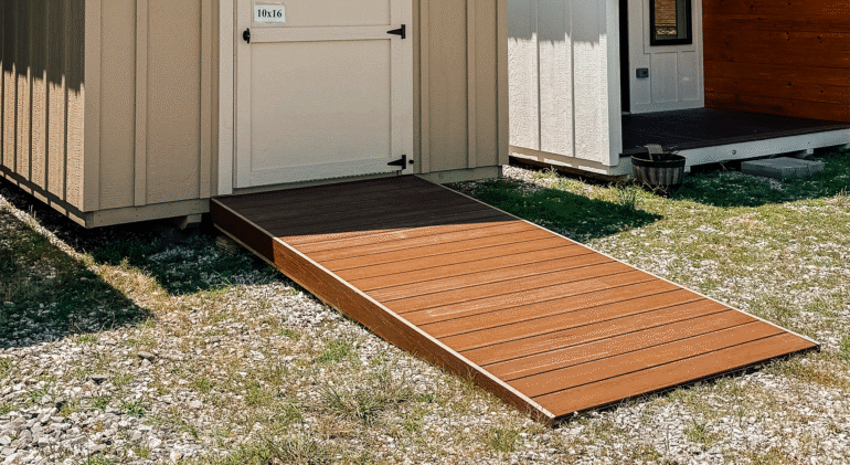 A small shed with a beige exterior featuring a brown composite deck ramp made of Trex boards, providing easy access to the entrance.