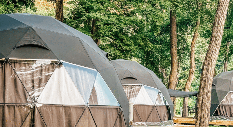 Green glamping tents on wooden decks in the forest.