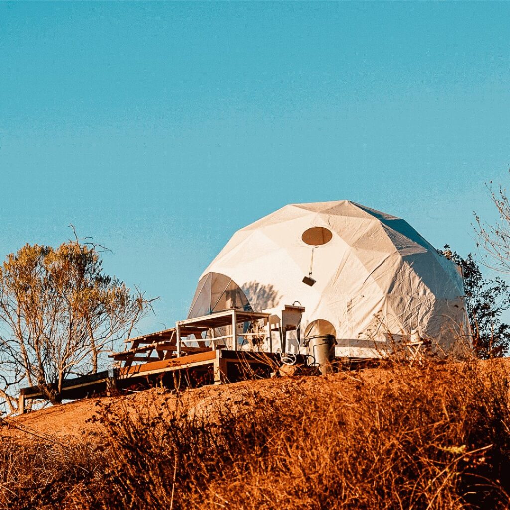 A white geodesic tent on a wooden deck.