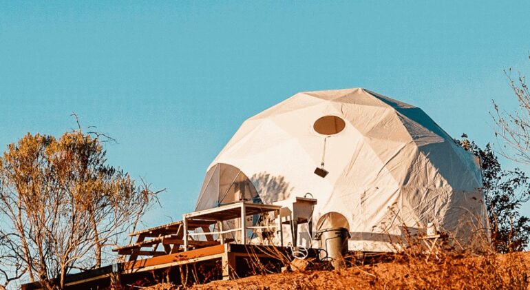 A white geodesic tent on a wooden deck.